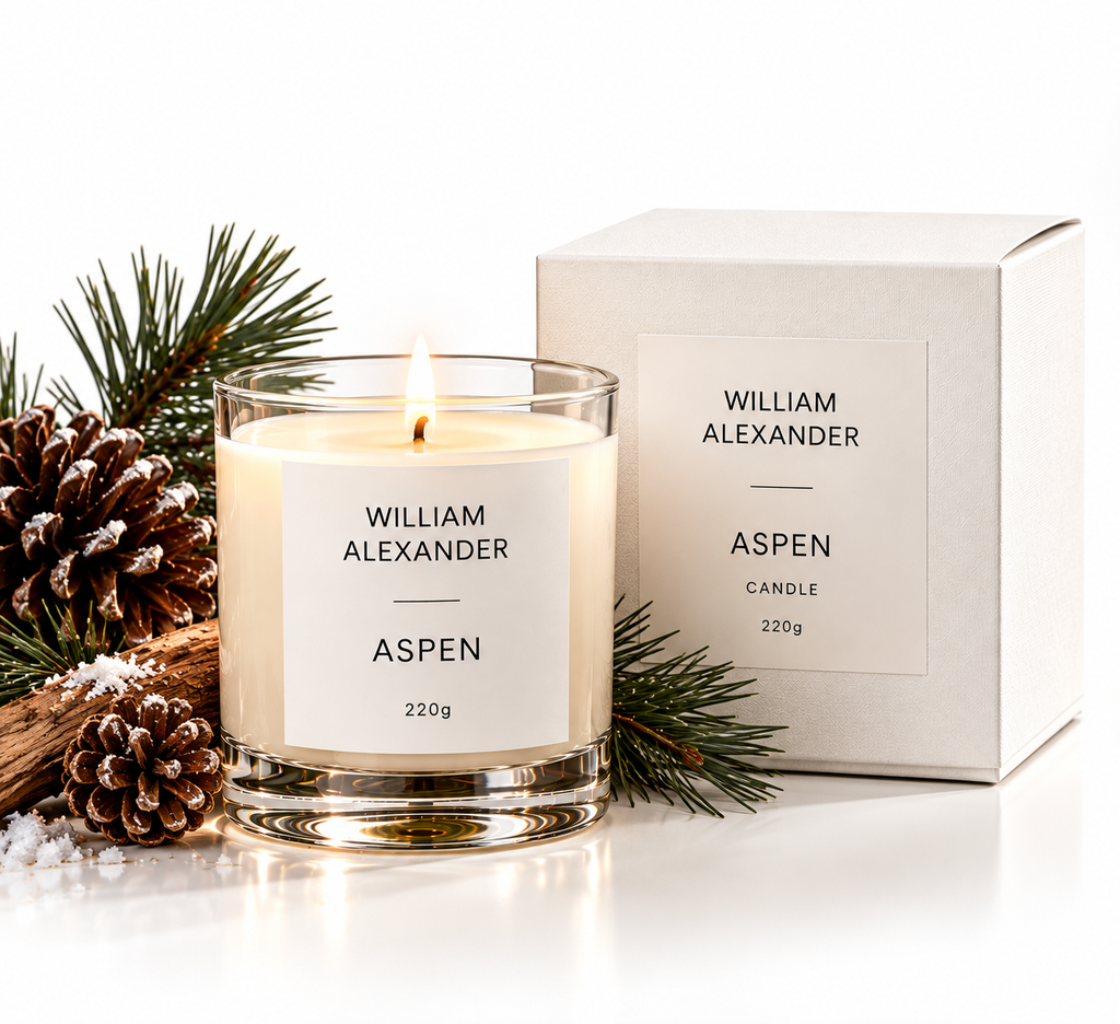 Aspen Winter Pine Christmas Candle 220g alight beside its William Alexander gift box with pine cones