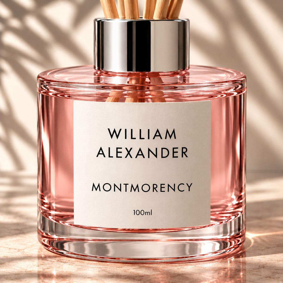 Close-up of the William Alexander Montmorency Black Cherry & Vanilla reed diffuser in pink-tinted glass with natural rattan reeds