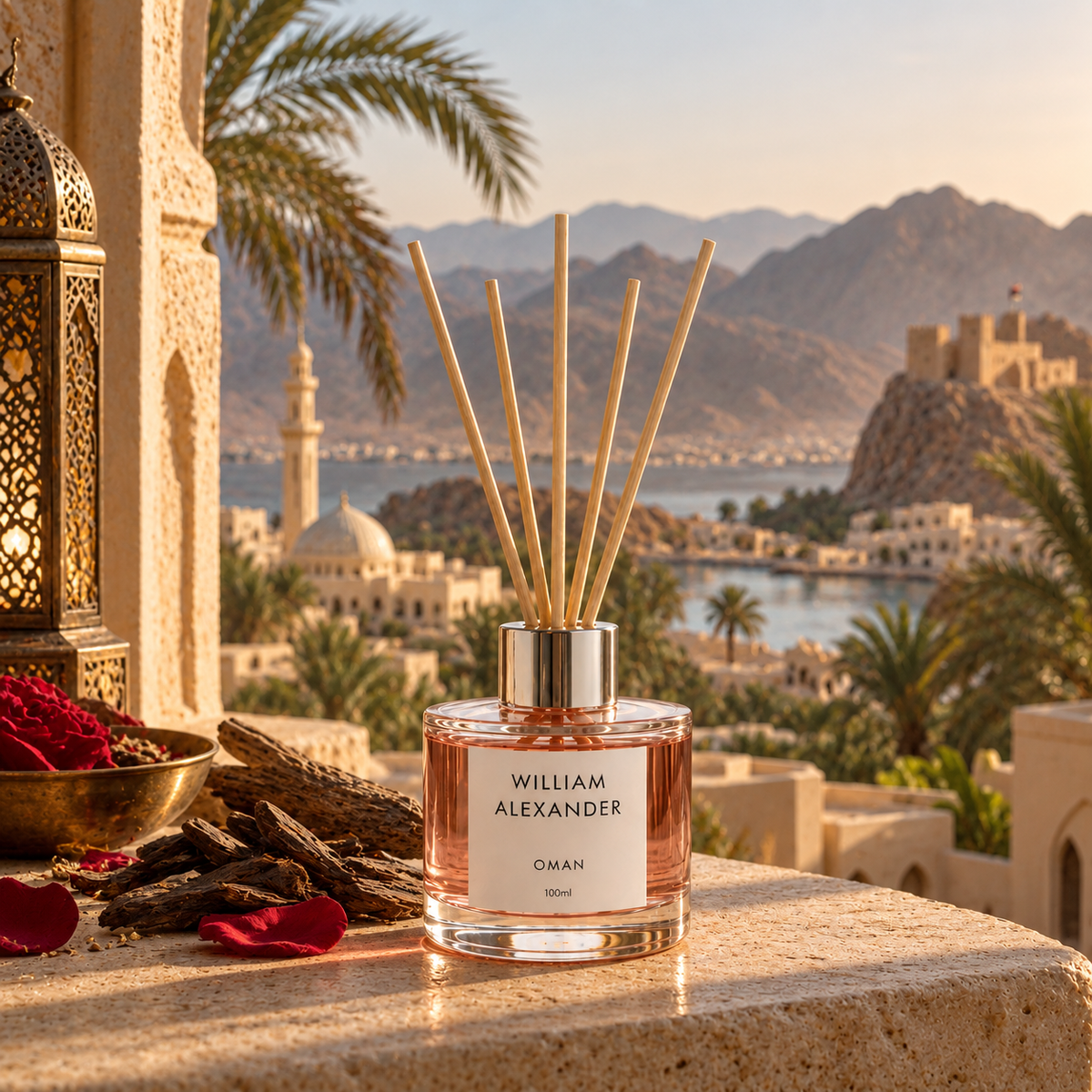 Oman Rose Oud Reed Diffuser 120ml on a terrace ledge with palm trees and Omani coastline behind